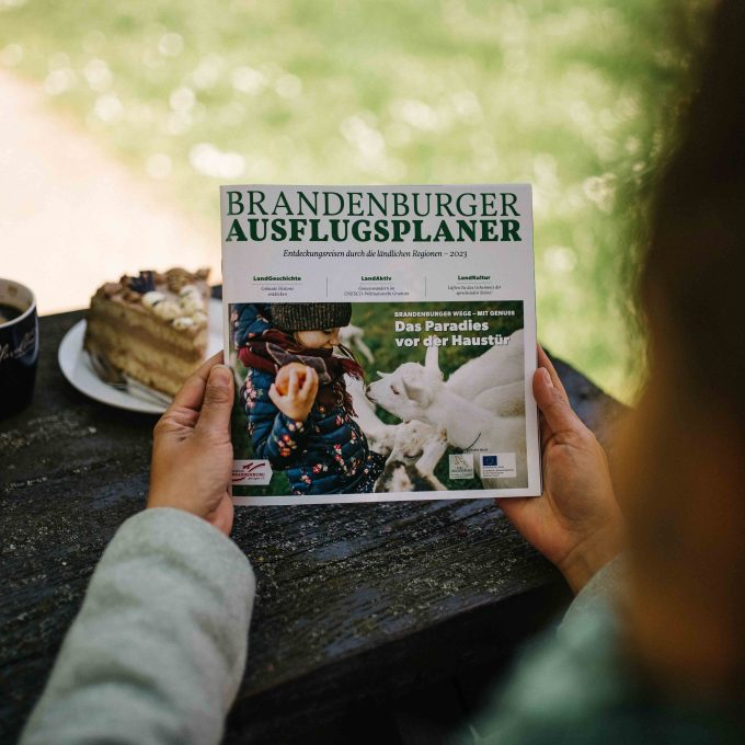 Broschüre Brandenburger Ausflugsplaner 2023 in den Händen gehalten mit Blick auf die Titelseite