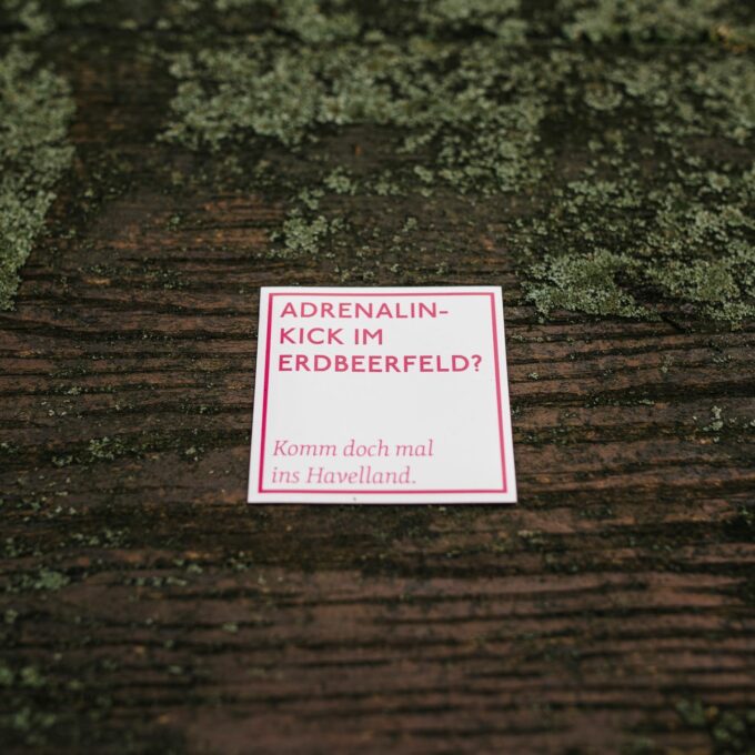 quadratischer Spruchmagnet, weiß mit pinker Aufschrift "Adrenalinkick im Erdbeerfeld? Komm doch mal ins Havelland."