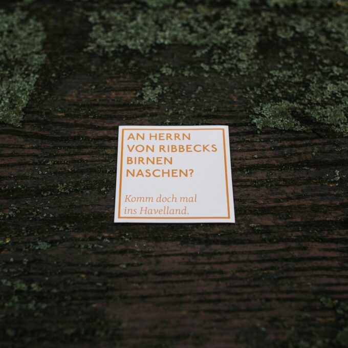 quadratischer Spruchmagnet, weiß mit orangener Aufschrift "An Herrn von Ribbecks Birnen naschen? Komm doch mal ins Havelland."