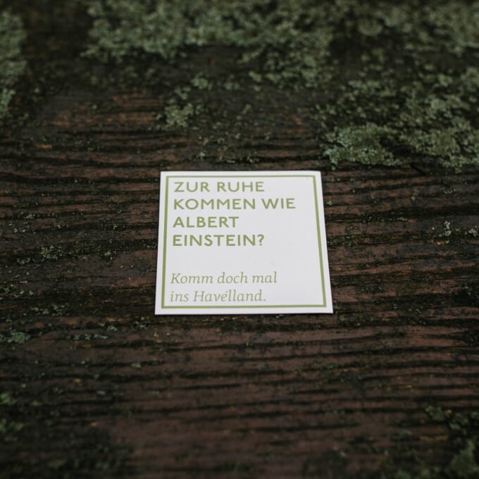 quadratischer Spruchmagnet, weiß mit grüner Aufschrift "Zur Ruhe kommen wie Albert Einstein? Komm doch mal ins Havelland."